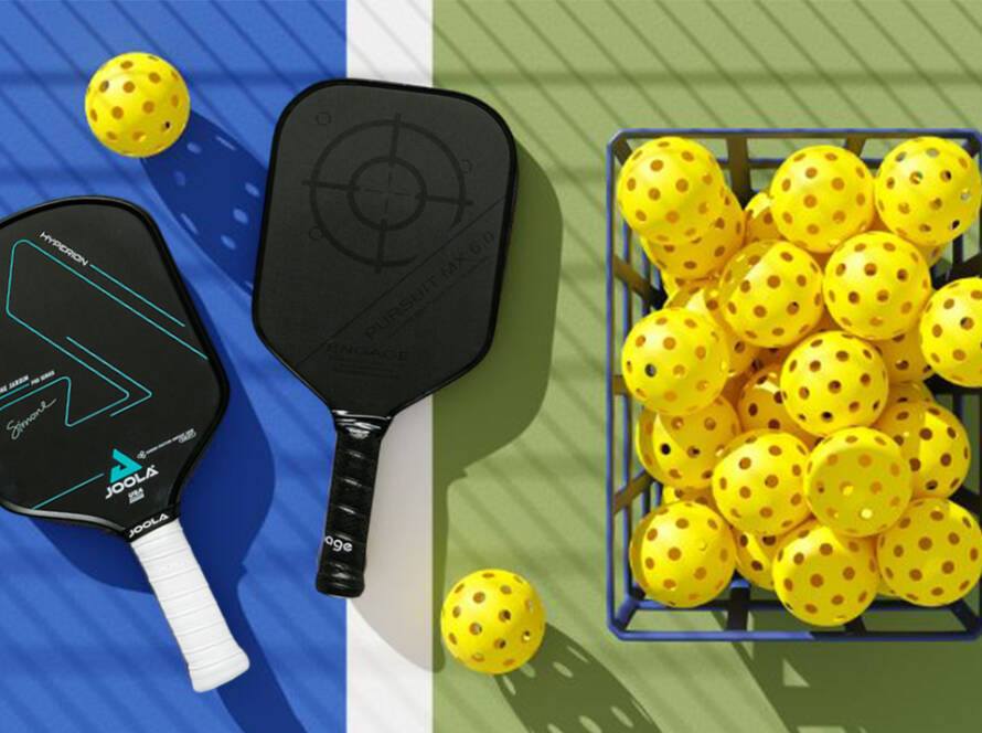 Pickleball paddles with a basket of yellow pickleballs on court